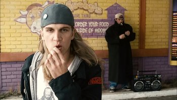 Movie still from “Clerks II” (2006), directed by Kevin Smith – A man with long blonde hair wearing a baseball cap; Medium shot, Over the shoulder angle