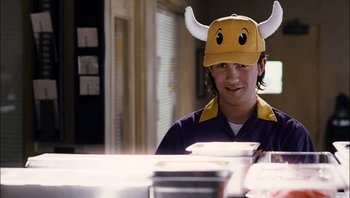 Movie still from “Clerks II” (2006), directed by Kevin Smith – A young man wearing a hat with horns on top of his head; Medium shot, Over the shoulder angle