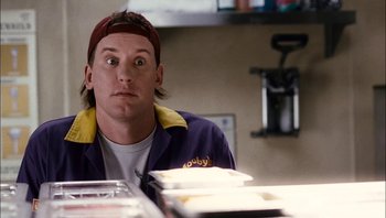 Movie still from “Clerks II” (2006), directed by Kevin Smith – A man sitting in front of a pile of papers; Close Up shot, Low angle