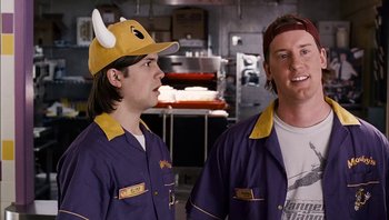 Movie still from “Clerks II” (2006), directed by Kevin Smith – Two men in purple work clothes and a yellow hat; Medium shot, Over the shoulder angle