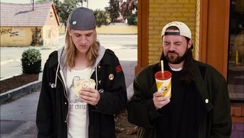 Movie still from “Clerks II” (2006), directed by Kevin Smith – A man and a woman holding hot dogs and a drink; Medium shot, Low angle