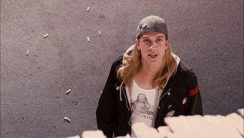 Movie still from “Clerks II” (2006), directed by Kevin Smith – A man with long blonde hair wearing a baseball cap; Medium shot, High angle