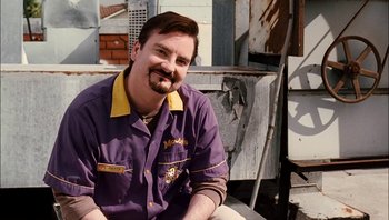 Movie still from “Clerks II” (2006), directed by Kevin Smith – A man with a beard sitting on the ground; Medium shot, Low angle