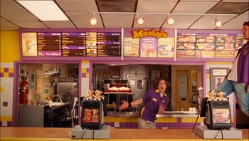 Movie still from “Clerks II” (2006), directed by Kevin Smith – A man standing in front of a counter in a restaurant; Wide shot, Over the shoulder angle