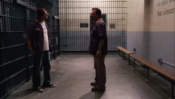Movie still from “Clerks II” (2006), directed by Kevin Smith – A man and a woman standing next to each other in a jail cell; Wide shot, Over the shoulder angle