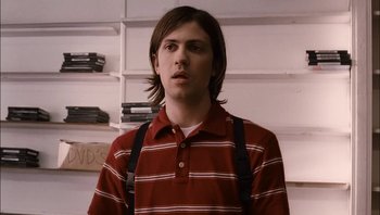 Movie still from “Clerks II” (2006), directed by Kevin Smith – A man with long hair wearing a red and white striped shirt and black suspenders; Close Up shot, Over the shoulder angle