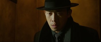 Movie still from “Cliff Walkers” (2021), directed by Yimou Zhang – A man wearing a hat and a tie; Close Up shot, Low angle