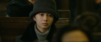 Movie still from “Cliff Walkers” (2021), directed by Yimou Zhang – A young woman wearing a hat and a sweater; Close Up shot, Over the shoulder angle