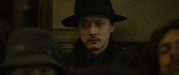 Movie still from “Cliff Walkers” (2021), directed by Yimou Zhang – A man wearing a black hat and a black coat; Close Up shot, Low angle