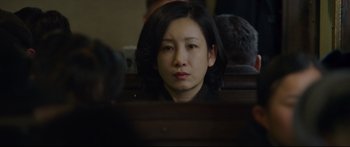 Movie still from “Cliff Walkers” (2021), directed by Yimou Zhang – A woman sitting in front of a mirror in a courtroom; Close Up shot, Over the shoulder angle
