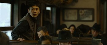 Movie still from “Cliff Walkers” (2021), directed by Yimou Zhang – A man standing in front of a group of people; Medium shot, Over the shoulder angle