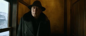 Movie still from “Cliff Walkers” (2021), directed by Yimou Zhang – An older man wearing a hat and a black coat; Close Up shot, Low angle