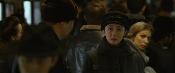 Movie still from “Cliff Walkers” (2021), directed by Yimou Zhang – A woman in a hat and a coat looking at the camera; Close Up shot, Over the shoulder angle