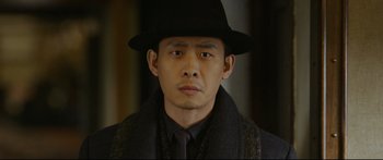 Movie still from “Cliff Walkers” (2021), directed by Yimou Zhang – A person wearing a hat and a coat; Close Up shot, Over the shoulder angle