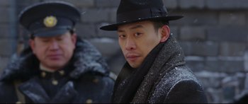 Movie still from “Cliff Walkers” (2021), directed by Yimou Zhang – A man wearing a black hat and a black coat; Close Up shot, Over the shoulder angle