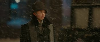 Movie still from “Cliff Walkers” (2021), directed by Yimou Zhang – A young girl wearing a coat and hat in the snow; Medium shot, Over the shoulder angle