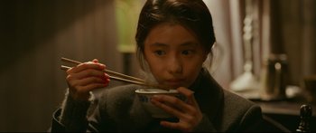 Movie still from “Cliff Walkers” (2021), directed by Yimou Zhang – A woman eating a bowl with chopsticks in her hands; Close Up shot, Over the shoulder angle
