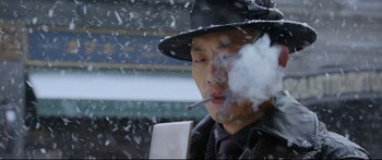 Movie still from “Cliff Walkers” (2021), directed by Yimou Zhang – A man smoking a cigarette while standing in the snow; Close Up shot, Low angle
