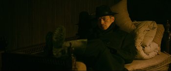 Movie still from “Cliff Walkers” (2021), directed by Yimou Zhang – A man wearing a hat and a black coat; Medium shot, Low angle