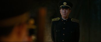 Movie still from “Cliff Walkers” (2021), directed by Yimou Zhang – A man in a military uniform standing in front of a brick wall; Medium shot, Over the shoulder angle