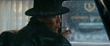 Movie still from “Cliff Walkers” (2021), directed by Yimou Zhang – A man wearing a black hat smoking a cigarette; Close Up shot, Low angle