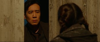 Movie still from “Cliff Walkers” (2021), directed by Yimou Zhang – A man standing next to another man in a dark room; Close Up shot, Over the shoulder angle