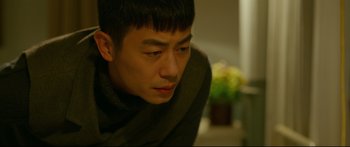 Movie still from “Cliff Walkers” (2021), directed by Yimou Zhang – A man with a scarf on his head looking at the camera; Close Up shot, Over the shoulder angle