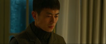 Movie still from “Cliff Walkers” (2021), directed by Yimou Zhang – A young man with short black hair looking down at his face; Close Up shot, Over the shoulder angle