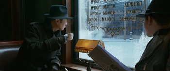 Movie still from “Cliff Walkers” (2021), directed by Yimou Zhang – A man sitting at a table drinking a cup of coffee; Medium shot, Over the shoulder angle