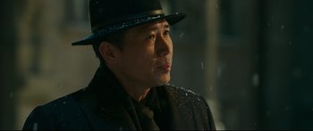 Movie still from “Cliff Walkers” (2021), directed by Yimou Zhang – A man wearing a black hat and a black coat; Close Up shot, Over the shoulder angle