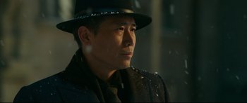 Movie still from “Cliff Walkers” (2021), directed by Yimou Zhang – A man wearing a black hat and a black coat; Close Up shot, Low angle
