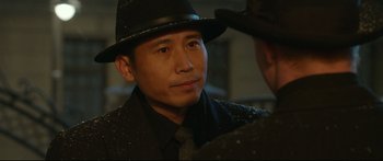 Movie still from “Cliff Walkers” (2021), directed by Yimou Zhang – A man wearing a hat and a tie; Close Up shot, Over the shoulder angle