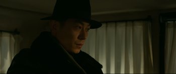 Movie still from “Cliff Walkers” (2021), directed by Yimou Zhang – A man wearing a black hat and a black coat; Close Up shot, Low angle