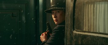 Movie still from “Cliff Walkers” (2021), directed by Yimou Zhang – A woman holding a gun while standing next to a wall; Close Up shot, Low angle