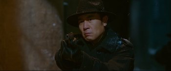 Movie still from “Cliff Walkers” (2021), directed by Yimou Zhang – A man in a hat holding a gun in his hand; Close Up shot, Low angle