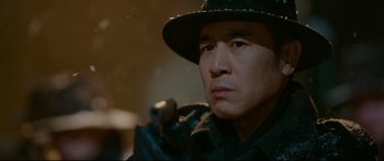 Movie still from “Cliff Walkers” (2021), directed by Yimou Zhang – A person wearing a hat and holding a gun; Close Up shot, Low angle