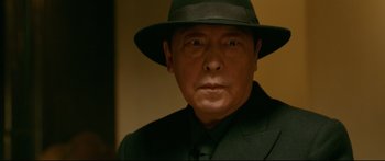 Movie still from “Cliff Walkers” (2021), directed by Yimou Zhang – A person wearing a suit and a hat; Close Up shot, Low angle