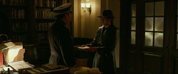 Movie still from “Cliff Walkers” (2021), directed by Yimou Zhang – A woman in a hat is handing a book to a man in a uniform; Medium shot, Over the shoulder angle
