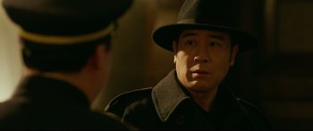 Movie still from “Cliff Walkers” (2021), directed by Yimou Zhang – A man wearing a black hat and a black coat; Close Up shot, Over the shoulder angle