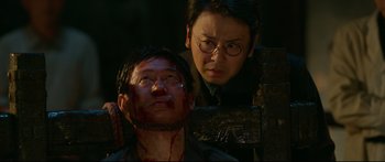 Movie still from “Cliff Walkers” (2021), directed by Yimou Zhang – A man with a bloody face and a man with glasses; Close Up shot, Over the shoulder angle