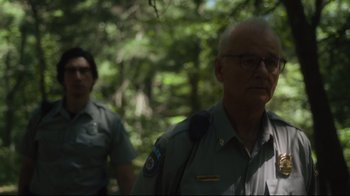 Movie still from “The Dead Don't Die” (2019), directed by Jim Jarmusch – Two men in the woods with trees in the background; Close Up shot, Over the shoulder angle