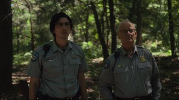 Movie still from “The Dead Don't Die” (2019), directed by Jim Jarmusch – A man and a man standing next to each other in the woods; Medium shot, Over the shoulder angle