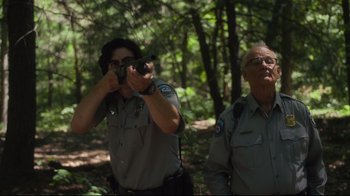 Movie still from “The Dead Don't Die” (2019), directed by Jim Jarmusch – Two men in the woods looking at something on a video camera; Medium shot, Low angle