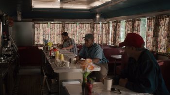 Movie still from “The Dead Don't Die” (2019), directed by Jim Jarmusch – A man sitting at a table in front of a woman; Medium shot, Over the shoulder angle