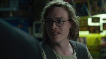 Movie still from “The Dead Don't Die” (2019), directed by Jim Jarmusch – A woman with glasses is smiling for the camera; Close Up shot, Over the shoulder angle