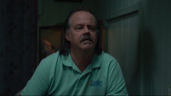 Movie still from “The Dead Don't Die” (2019), directed by Jim Jarmusch – A man with long black hair and a mustache wearing a green shirt; Close Up shot, Low angle