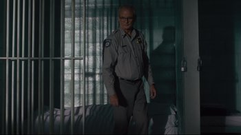 Movie still from “The Dead Don't Die” (2019), directed by Jim Jarmusch – An older man in a uniform standing in front of a window; Medium shot, Over the shoulder angle