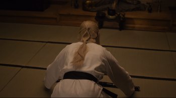 Movie still from “The Dead Don't Die” (2019), directed by Jim Jarmusch – A woman in a white shirt and a black belt is kneeling down; Medium shot, High angle