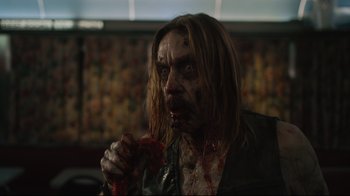 Movie still from “The Dead Don't Die” (2019), directed by Jim Jarmusch – A man eating something with blood on his face; Close Up shot, Over the shoulder angle