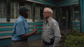 Movie still from “The Dead Don't Die” (2019), directed by Jim Jarmusch – Two men standing next to each other on a street; Medium shot, Over the shoulder angle